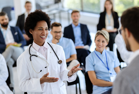 Happy African American female doctor talking to businessman holding seminar in convention hall shutterstock 1808612890 475x320px