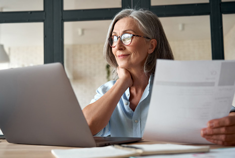 Smiling mature middle aged business woman using laptop working on computer sitting at desk shutterstock 1818524411 475x32opx